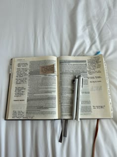 an open book on a bed with a pen next to it and a notepad