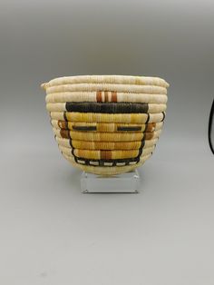 a woven basket sitting on top of a metal stand next to a black and white mirror