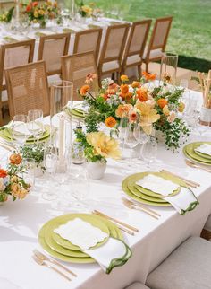 the table is set with place settings and flowers in vases, plates, and napkins