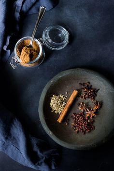 an overhead view of spices and cinnamon on a plate next to a glass bowl with spoons