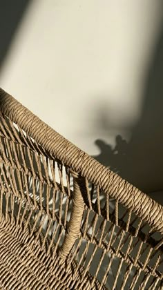 the shadow of a person's hand is cast on a wicker chair cushion