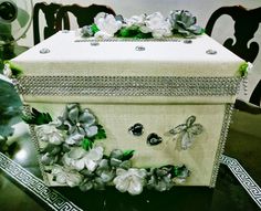 a decorative box sitting on top of a table next to a vase with flowers in it