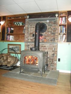 a wood burning stove sitting inside of a living room next to a book shelf filled with books