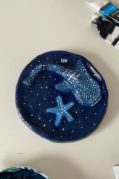 a blue plate sitting on top of a table next to a bowl and paintbrush