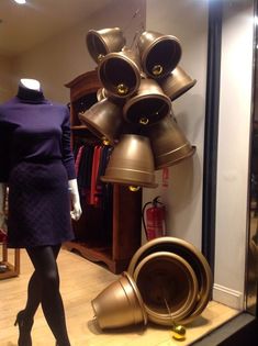 a mannequin wearing a purple dress stands in front of an assortment of bells