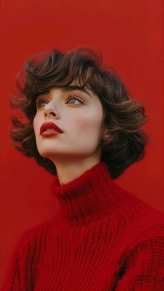 a woman with short hair wearing a red turtle neck sweater and looking up into the sky