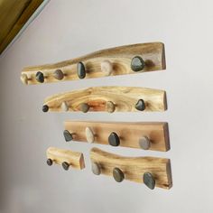 three wooden pegs with rocks on them are hanging from the side of a wall