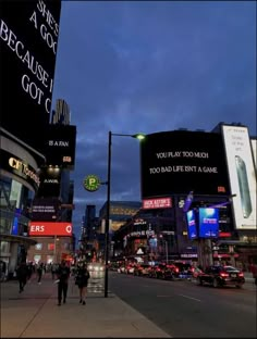 people are walking down the street in front of billboards and buildings at night time