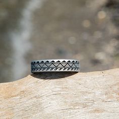 a black and white ring sitting on top of a piece of wood