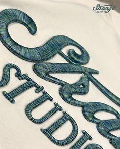 the letters are made out of yarn and stitched together to make an embroidered t - shirt