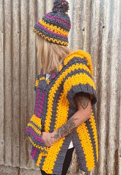 a woman wearing a yellow and black crochet ponchy with a hat on her head