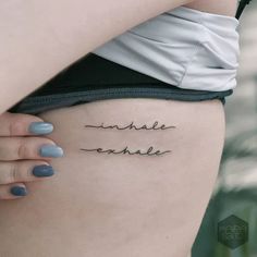 a woman's lower thigh with the words enhale exhale on it, in cursive font