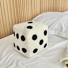 a white and black dice sitting on top of a bed next to a roll of toilet paper