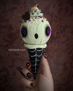 a hand holding an ice cream cone decorated with spooky eyes