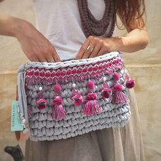 a woman holding a gray and pink purse