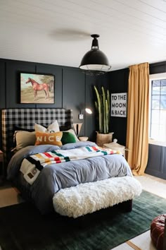 a bedroom with black walls, plaid bedding, and rugs on the floor