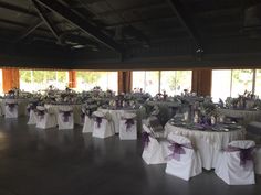 the tables are set up with white linens and purple sashes on them for a formal function