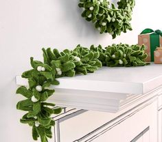 a christmas wreath on top of a white dresser