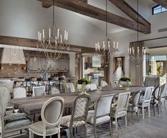 a large dining room table with chairs and chandelier in front of an open floor plan