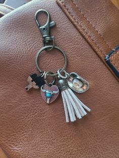 a keychain with two charms attached to it on a brown leather bag,