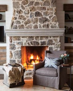 a living room with a stone fireplace and chair