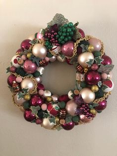 a christmas wreath hanging on the wall with baubles and other ornaments around it