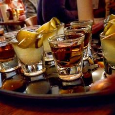 several glasses filled with different types of drinks on a tray in front of some people