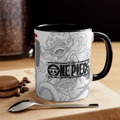 a coffee mug sitting on top of a wooden table next to a spoon and cup