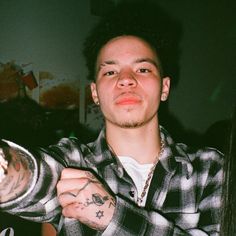 a young man with tattoos on his arms holding something in one hand and looking at the camera