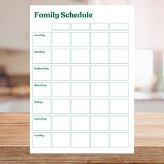 a family schedule sitting on top of a wooden table in front of a kitchen counter