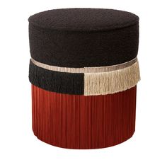 a black, red and white ottoman with fringes on the top is sitting in front of a white background