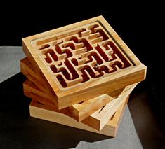 three wooden boxes with carved designs on them sitting on top of each other in front of a black background