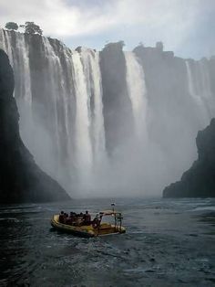 a boat with people on it in front of a waterfall