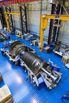 the inside of a factory with machinery and workers working on it's equipment, including an engine