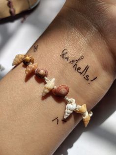 a woman's arm with shells and writing on it