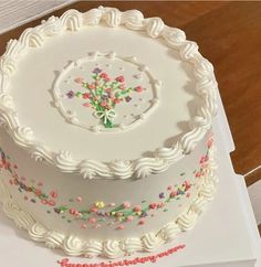 a white cake with sprinkles on it sitting on top of a table