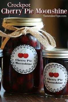 jars filled with cherries sitting on top of a wooden table