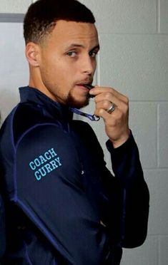 a man brushing his teeth while wearing a coach's jacket and holding a toothbrush