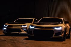 two chevrolet camaros are parked in the dark