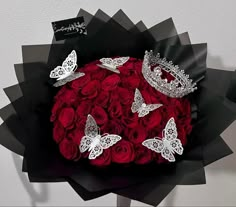 a bouquet of roses with tiaras and butterflies on it is shown in front of a white wall