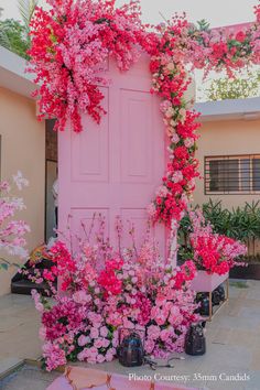 a pink door surrounded by flowers and potted plants