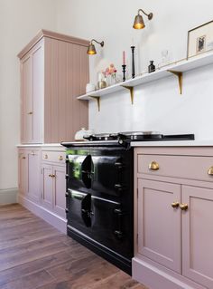 a black stove top oven sitting inside of a kitchen next to wooden floors and cabinets