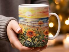 a person holding a coffee mug with sunflowers painted on the outside and inside