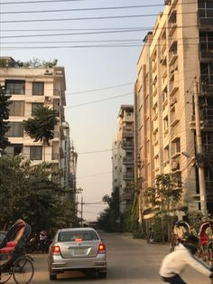 a person riding a bike down a street next to tall buildings and parked cars on the side of the road