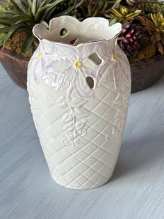 a white vase sitting on top of a wooden table next to succulents