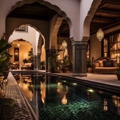 an indoor swimming pool surrounded by stone pillars and arches with lights on each side in front of it