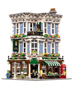 a lego model of a building with flowers on the balconies and people standing outside