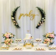 a table topped with cakes and cupcakes next to a white drape curtain