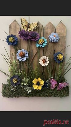 a wooden fence with flowers and butterflies on it's side, in front of a white wall