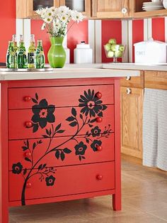 a red cabinet with flowers painted on the front and bottom, sitting in a kitchen